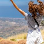 a woman with her hair in the air on top of a hill
